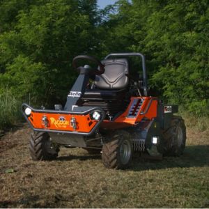 the Stella Racoon 110 Ride-on Flail Mower parked in a clearing, in front of some trees