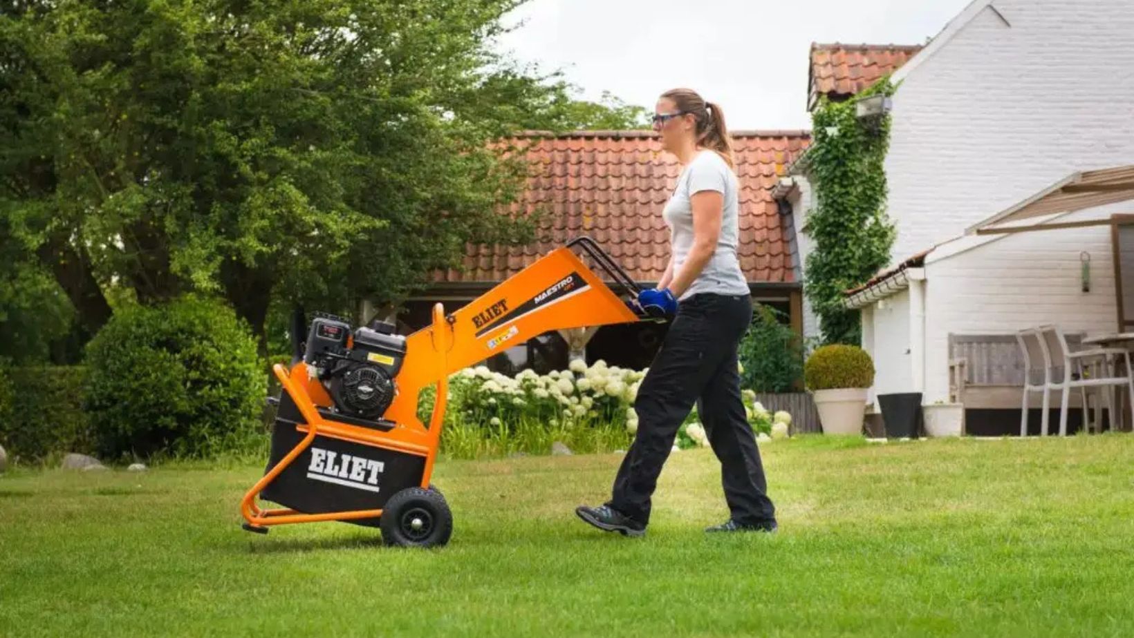 a woman pushing the Eliet Maestro City Petrol Garden Shredder across a lawn