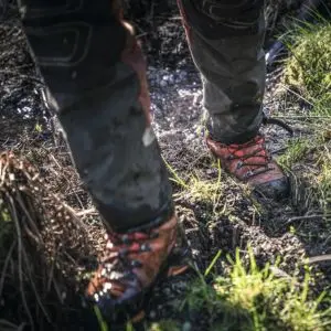 a close up of someone wearing chainsaw trousers and Husqvarna Technical 24 leather chainsaw boots on damp ground