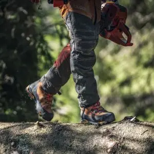 someone walking along a log, while wearing Husqvarna Technical 24 leather chainsaw boots