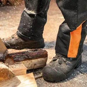 a close up of someone wearing chainsaw trousers and boots