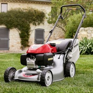 a Honda Izy HRG 466 PK Petrol Lawn Mower on a lawn, in front of a house