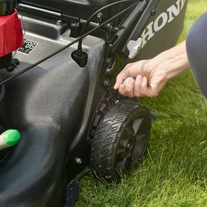 a close up of someone setting the cutting height on a Honda HRN lawnmower