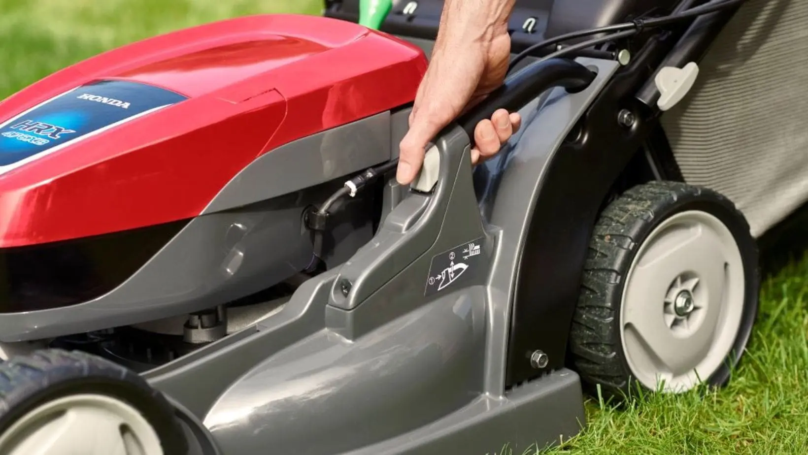 a close up of someone adjusting a Honda HRX lawnmower's cutting height