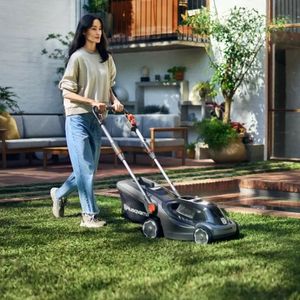 a woman passing by the house as she mows her lawn using a Husqvarna lawnmower