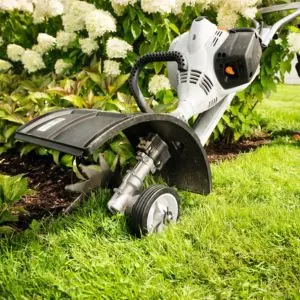 the STIHL FC-MM Lawn Edge Trimmer MultiTool operating between a lawn and garden border