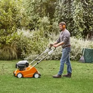 a man wearing ear defenders, operating the STIHL RL 540 Petrol Scarifier on a lawn