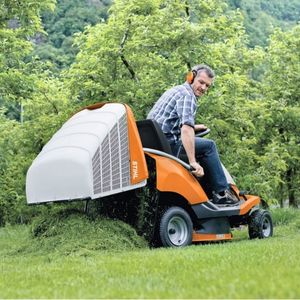 a man in the driver's seat of the STIHL RT 4082 Petrol Ride-on Lawn Mower, automatically emptying the grass cuttings box onto a lawn