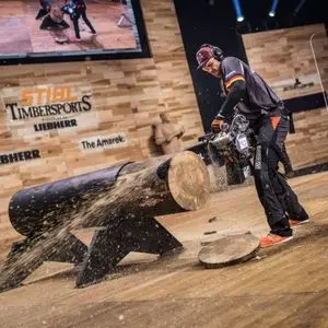 a man onstage at The STIHL Timbersports event, using a STIHL chainsaw to cut a log