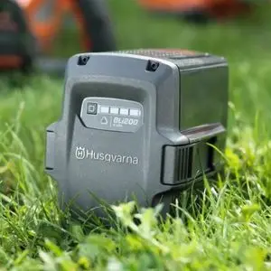 a grey Husqvarna BLi200 battery sat on a lawn