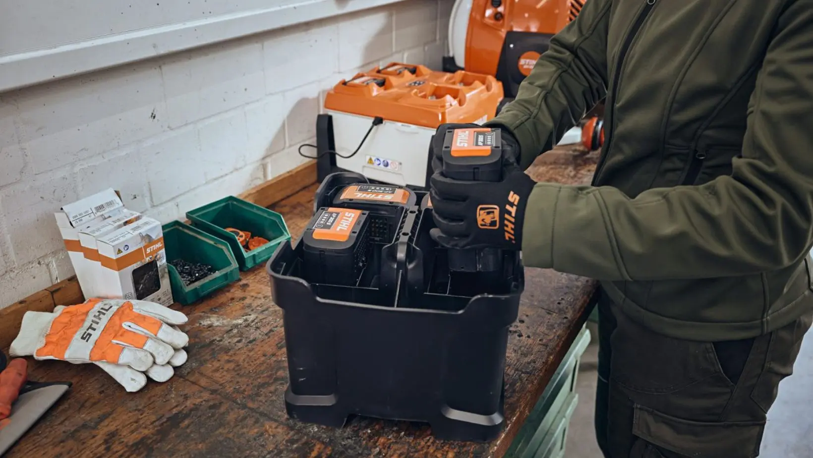 a man packing STIHL lithium-ion batteries into a battery storage box, which is positioned on a workbench