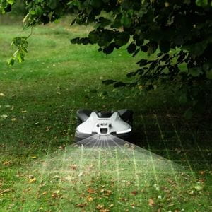 a Husqvarna Automower on a lawn, underneath overhanging tree branches, with grid graphics demonstrating its use of AI vision technology