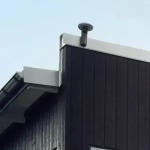 a Husqvarna EPOS™ RS1 Reference Station fixed to the white trim at the top of a black-clad building