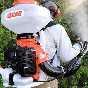 a rearview shot of a man wearing ear defenders, using an ECHO mist blower to apply treatment to trees
