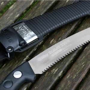 a close up of the Silky Zubat Pruning Saw and its sheath on a slatted wooden surface