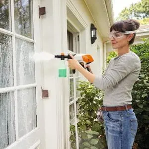 a woman cleaning a partially glazed door using the STIHL RCA 20 Cordless Handheld Pressure Washer