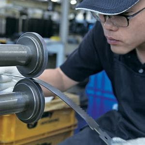 a young engineer, wearing a baseball cap and glasses, manufacturing a Silky saw