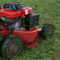 a red lawnmower mowing wet grass
