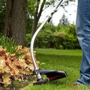 someone wearing blue jeans, using the ECHO GT-222ES Petrol Grass Trimmer to tidy the edge of a flowerbed