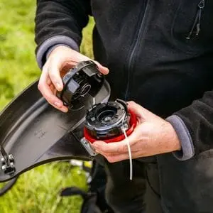 a close up of a man opening the trimmer head of a Honda Brushcutter UMR450