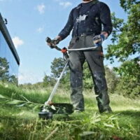 someone using a Husqvarna grass trimmer to cut down long grass