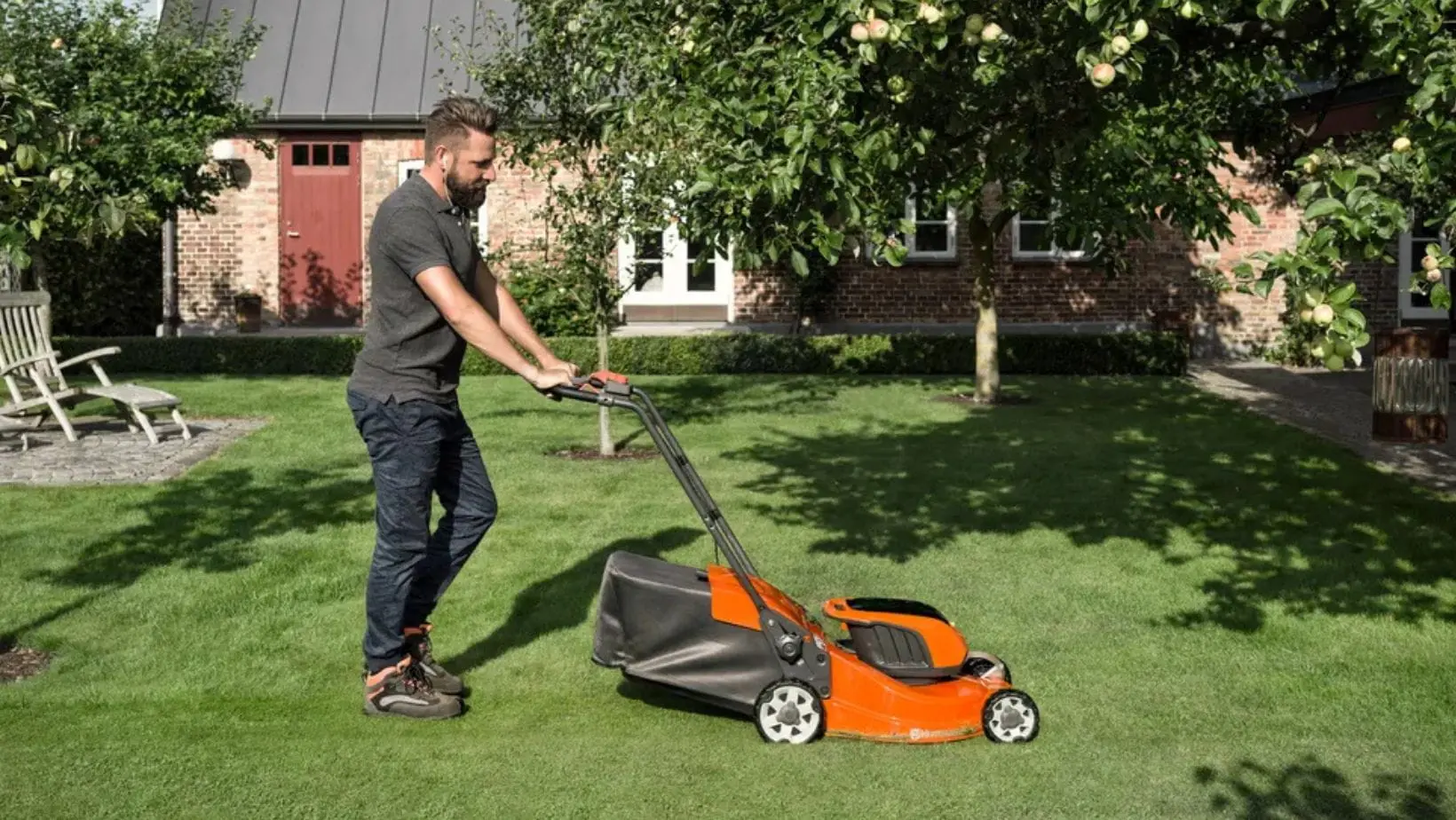 Husqvarna Mowers (1) a bearded man mowing a lawn using a Husqvarna lawnmower, with a house, trees, and garden furniture in the background