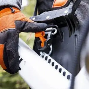 a close up of someone wearing gloves, adjusting a STIHL brushcutter harness