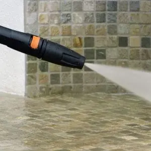 a close up of a black pressure washer cleaning a patio
