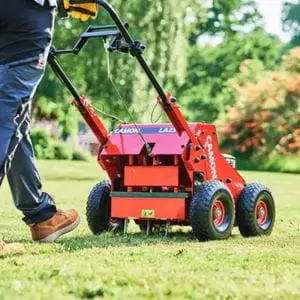 a rearview shot of the Camon LA25 Petrol Lawn Aerator's metal tines punching holes in a lawn