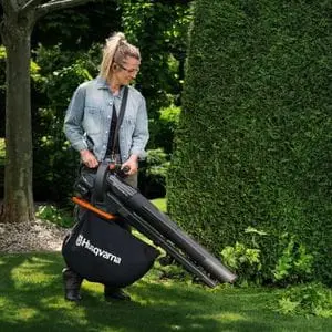 a woman collecting fallen leaves from a lawn using the Husqvarna Aspire™ BVX-P4A Blower Vacuum