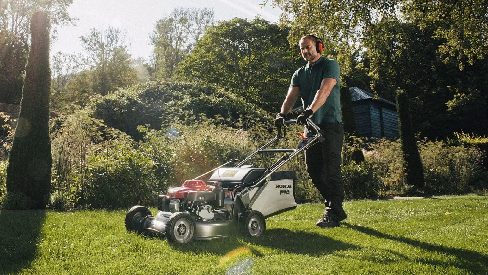 HRH 536 HX Mower 3 (1) a man using a Honda HRH 536 HX Lawn Mower to mow grass on a sunny day
