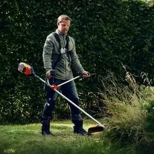 a man cutting long grass with the Husqvarna 325iR Cordless Brushcutter