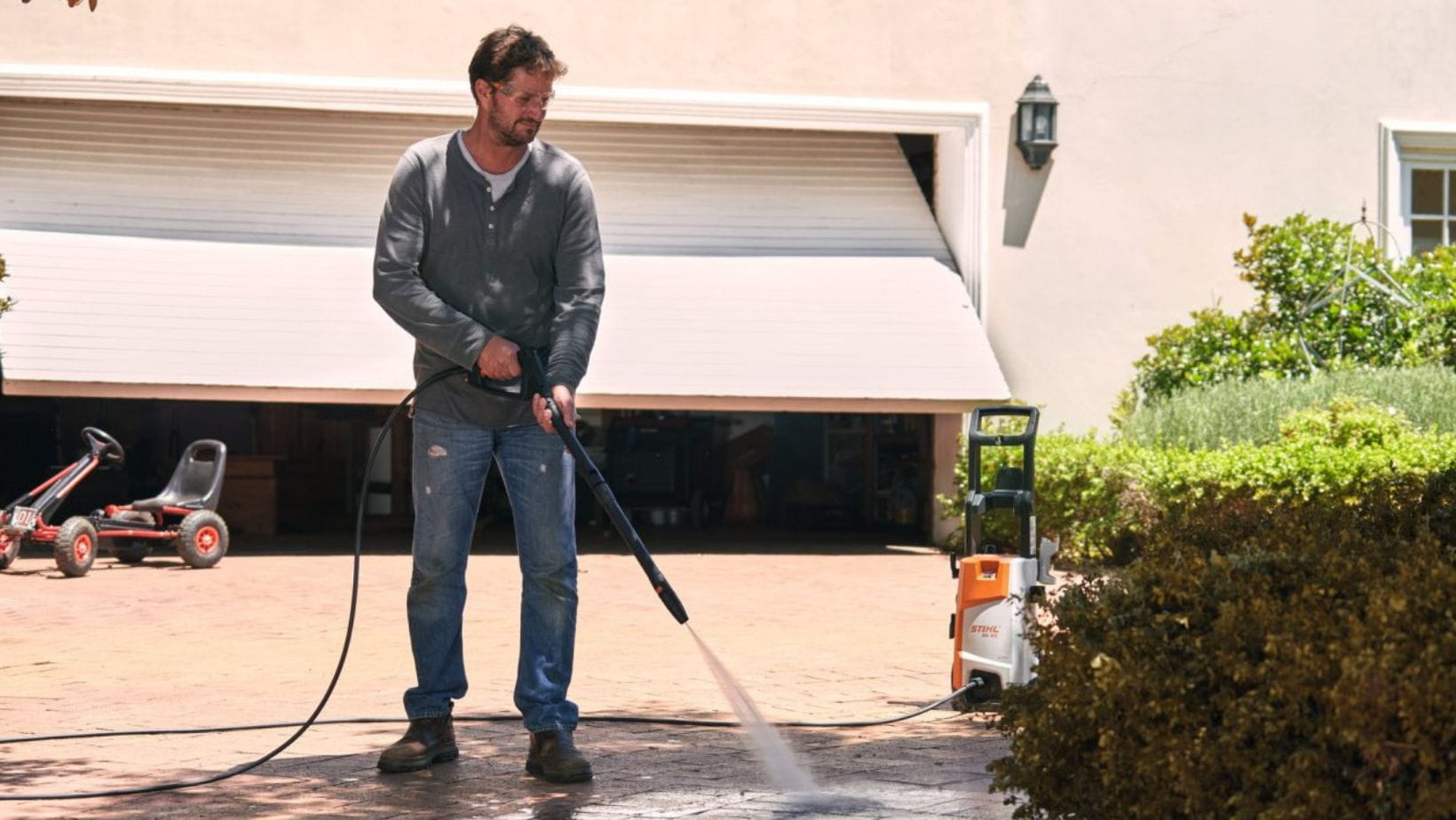 a man using the STIHL RE 90 Electric Pressure Washer to jet wash a driveway