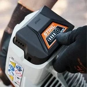 someone wearing black gloves, placing a STIHL AK 20 Battery in a cordless tool