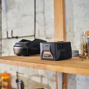 a STIHL battery and charger sat on a wooden shelf in a white-walled garage