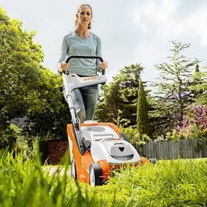 a woman mowing a lawn with a STIHL lawnmower