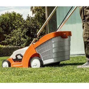 someone stood next to a STIHL mower, on a lawn, next to a house