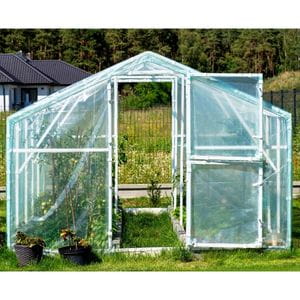 a greenhouse full of plants, positioned on a lawn