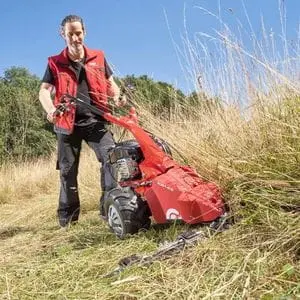a man cutting long grass on a slope using the AL-KO BM 5001-R IV Petrol Scythe Mower