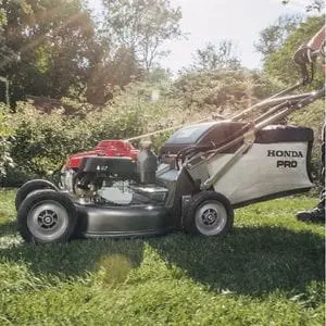 someone mowing a lawn in sunny conditions, using the Honda HRH 536 HX Petrol Lawnmower