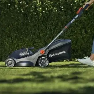 someone pushing the Husqvarna Aspire™ LC34-P4A Cordless Lawn Mower across a lawn