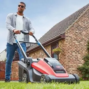 a man cutting a lawn near a bungalow, using the Toro eL43PST eMulticycler® 60V Cordless Lawn Mower