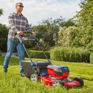 a man wearing sunglasses, mowing a large lawn using the Toro eS55AST eRecycler™ 60V Cordless Lawn Mower