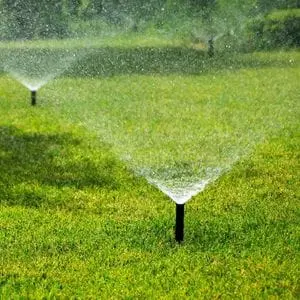2 water sprinklers on a large lawn