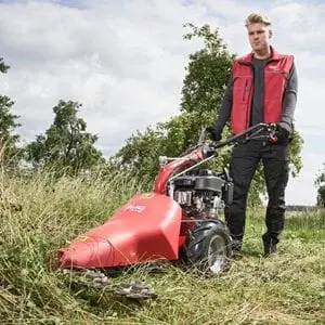 a man using the AL-KO Comfort BF 5002 R II Petrol Combi-Tool Power Unit with Scythe Mower Attachment to cut down long grass