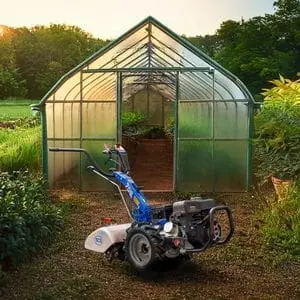 the BCS 706 PowerSafe® Two-Wheel Tractor parked outside the front of a greenhouse on a smallholding