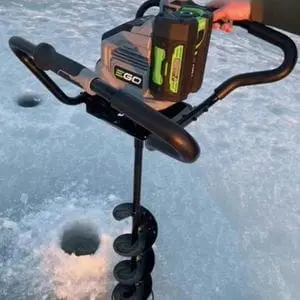 someone drilling a hole in ice using the EGO PHA7404E Cordless Earth and Ice Auger Power Head and auger bit