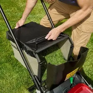 a man removing a full grass collector from a Honda HRX lawn mower
