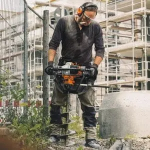 a man resembling Hulk Hogan, operating the STIHL BT 131 Petrol Earth Auger on a building site