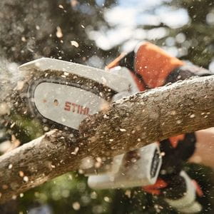 a close up of someone wearing protective gloves, cutting off a tree branch using the STIHL GTA 26 Cordless Pruner